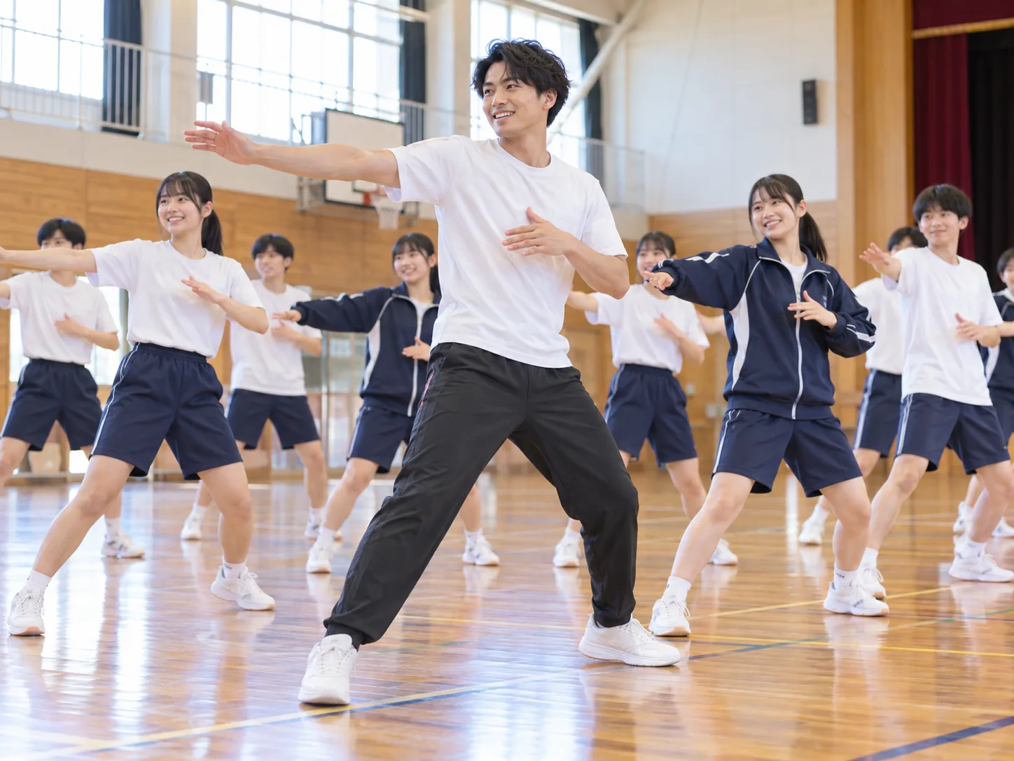 学校体育館で男性ダンス講師が中高生にダンスを指導するイメージ
